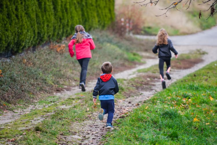 Wycieczka w przedszkolu. Na zdjęciu: dzieci na wycieczce przedszkolnej. Na zdjęciu: biegnące po trawie dzieci.
