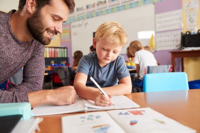   Jaką dokumentację prowadzi nauczyciel wspomagający w przedszkolu. Na zdjęciu: Nauczyciel pracuje z dzieckiem przy stoliku