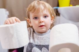 Wycieranie dzieciom pupy w przedszkolu obowiązek nauczyciela. Na zdjęciu dziecko trzymające dwie rolki papieru toaletowego