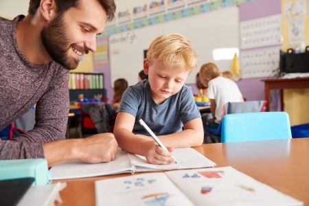   Jaką dokumentację prowadzi nauczyciel wspomagający w przedszkolu. Na zdjęciu: Nauczyciel pracuje z dzieckiem przy stoliku